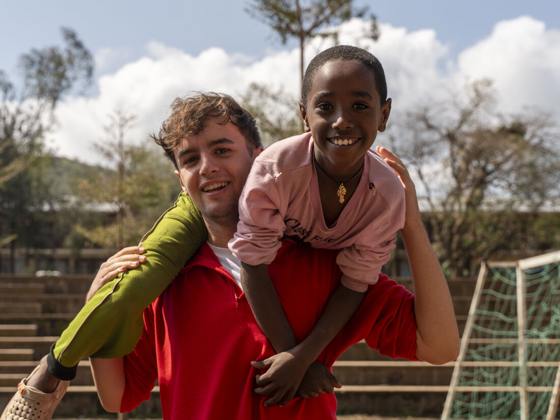 Alumno de ChezNous con un niño etíope a hombros en un campo de fútbol