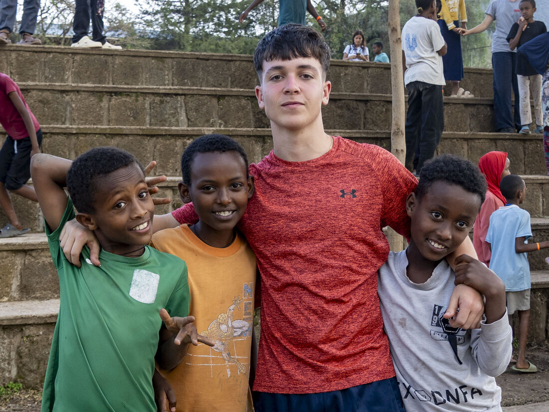 Alumno de ChezNous posando con tres niños locales en las gradas